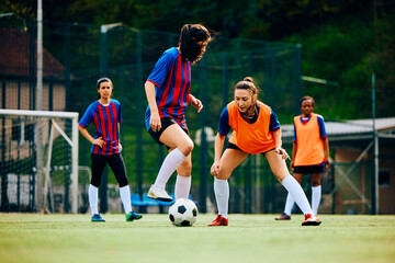 Young sportswomen playing soccer on training at stadium.