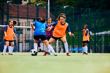 Women's soccer team having sports training on playing field.