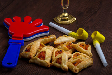 Homemade gomentash cookies for the holiday of Purim on a wooden table next to the rattle.