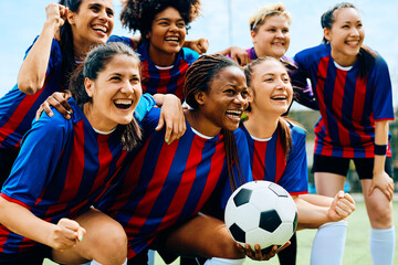 Happy women's soccer team celebrating victory on playing field.