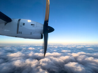 Naklejka na ściany i meble Spinning propeller of an airplane flying above the clouds in the blue sky