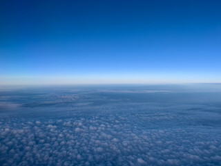 Airplane view of white cumulus clouds on turquoise horizon