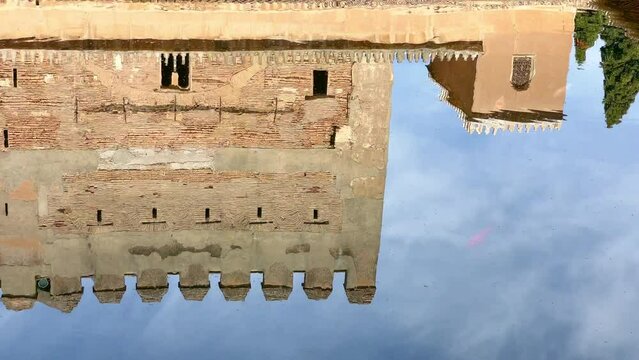 Comares Palace and Tower from the Court of Myrtles reflected in the yard pool, Nasrid Palace, Alhambra, Granada, Spain. Rippled water surface 4K footage.