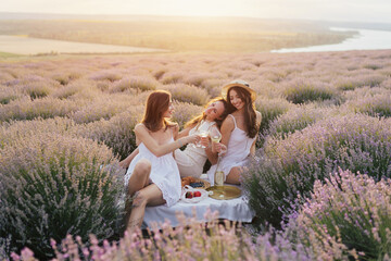 Cheerful friends enjoying a leisurely picnic on the lavender field with beautiful landscape. They having a picnic and having fun. 