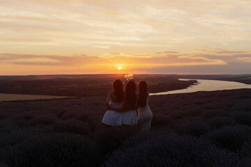 Silhouette of girlfriends enjoying their time together on a picnic at amazing sunset. Leisure and free time. Copy space.	
