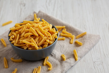 Homemade Raw Organic Caserecce Pasta in a Bowl on a white wooden background, side view.