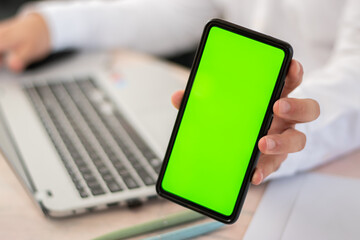 executive in his desk showing cell phone with chroma key front the camera.