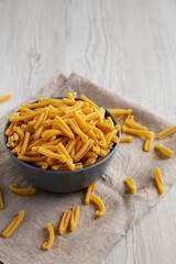 Homemade Raw Organic Caserecce Pasta in a Bowl on a white wooden background, side view. Space for text.