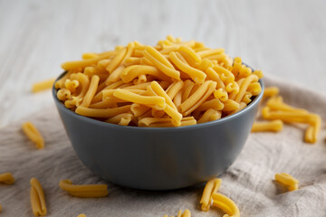 Homemade Raw Organic Caserecce Pasta in a Bowl on a white wooden background, low angle view. Close-up.