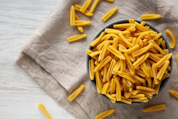 Homemade Raw Organic Caserecce Pasta in a Bowl on a white wooden background, top view. Flat lay, overhead, from above. Copy space.