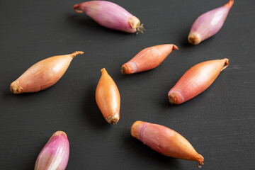 Raw Organic Shallots on a Black surface, side view.