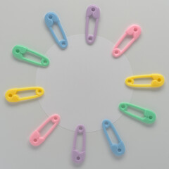 baby concept round white card on white background surrounded with multi color  toy plastic diaper safety pins
