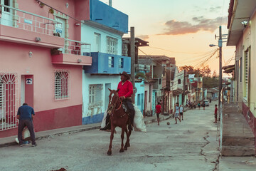 Workers on horseback through the streets of Trinidad in Cuba at sunset
