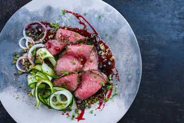 Traditional Commonwealth Sunday roast as sliced cold cuts roast beef with zucchini and capers in...