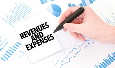 Businessman holding a black marker, notepad with text REVENUES AND EXPENSES, business concept