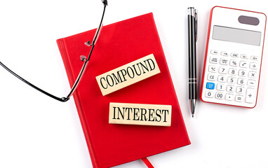 COMPOUND INTEREST text on wooden block on red notebook