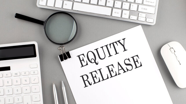 EQUITY RELEASE written on paper with office tools and keyboard on the grey background