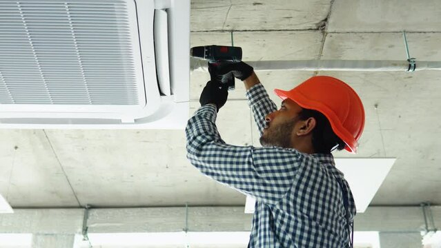 Indian young worker installs air conditioner in the office