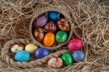 Fototapeta na wymiar Multicolored Easter eggs in a basket over straws. Pastel colored Easter eggs.