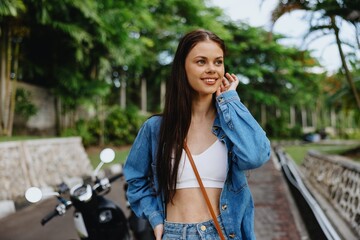 Portrait of a woman brunette smile with teeth walking outside against a backdrop of palm trees in the tropics, summer vacations and outdoor recreation, the carefree lifestyle of a freelance student.