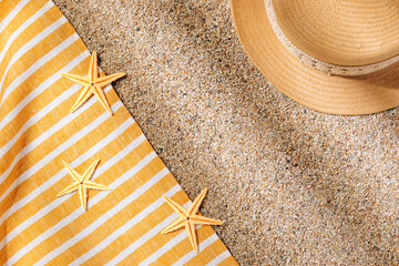 Straw hat and beach towel on the beach sand