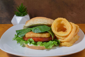 fish  sandwich top  with spinach  and  a side of onion rings