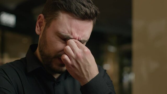 Close up anxious stressed Caucasian man tired upset guy rub dry irritated eyes feel pain ache eye strain sad male businessman crying tears bad vision discomfort suffer astigmatism syndrome headache