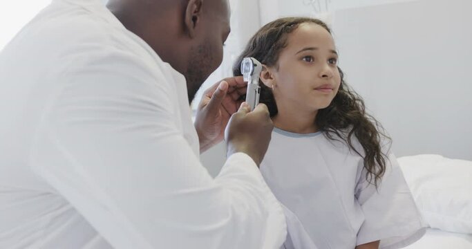 Happy diverse doctor examining sick girl patient with otoscopy in hospital in slow motion