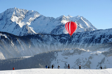Hot air balloon on the slopes of Courchevel ski resort by winter with Mont Blanc mountain behind