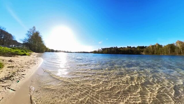 idyllischer See mit kristallklarem Wasser,, kleinen Wellen,  Sonnenschein blauer Himmel, Drohne