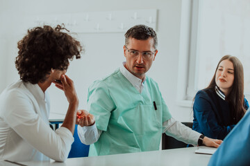 Fototapeta premium A group of multiethnic medical professionals including doctors, surgeons, and nurses are gathered in a hospital setting discussing patient care and using modern technology to address challenges in