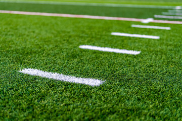 Late afternoon close up photo of hash marks on a synthetic turf football field.
