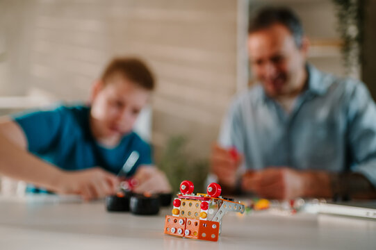 Focus on assembled toy on the table with blurred background of father and son.