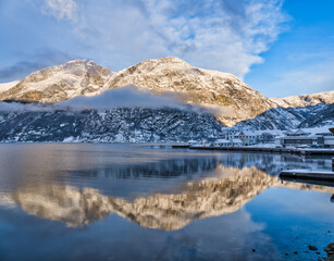 Waterfront buildings in Eidfjord village and mountains at sunset during winter on Hardangerfjord, Norway