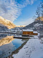 Waterfront colorful buildings in Eidfjord village and mountains at sunset during winter on Hardangerfjord, Norway
