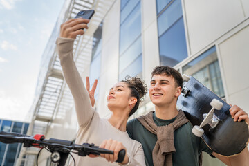 Fototapeta na wymiar Young man and woman teenager couple take selfies by modern building