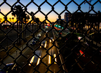 Obraz na płótnie Canvas Traffic on Pacific Coast Highway shot through a foreground of an in focus chain link fence