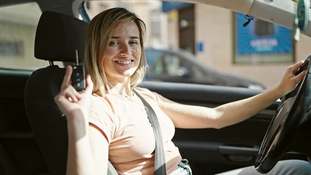 Young blonde woman smiling confident holding key of new car at street
