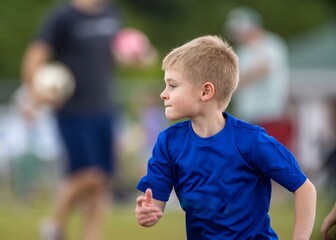 Young boy playing team soccer in blue uniform