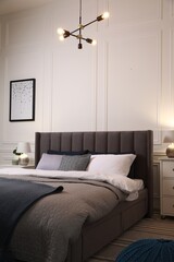 Comfortable bed with pillows and bedding in stylish room. Interior design - obrazy, fototapety, plakaty