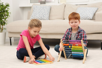 Children playing with different math game kits on floor in living room. Study mathematics with...