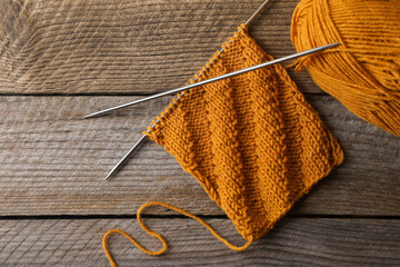 Soft orange yarn, knitting and metal needles on wooden table, flat lay