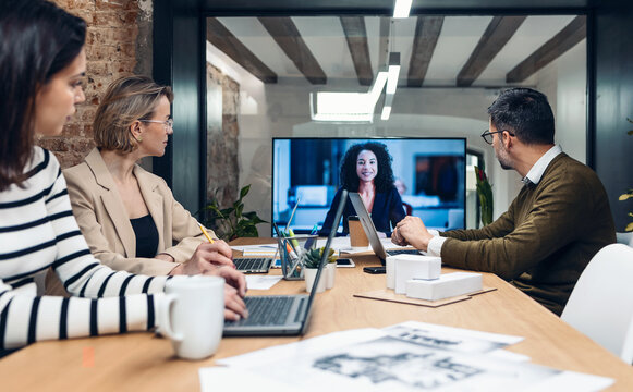 Smart business people working and talking of they new project while doing a video call with company director in modern office