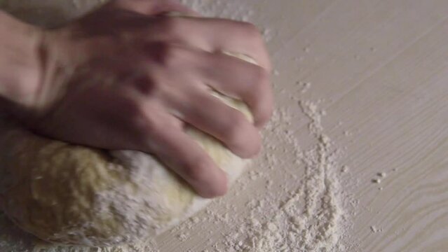One hand of young woman kneading dough on the table. Mother made bread or pizza at home