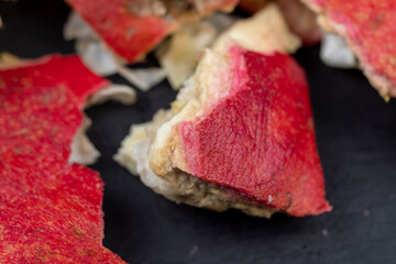 the peel of a red ripe pomegranate on a black board