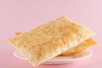 Two Fried Pastels (Pastel de Feira) on a plate, pink background, Lunch