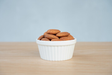 Ceramic bowl of almonds. Almond nut organic healthy snack vegan vegetarian. Bowl of almond nuts on rustic wooden table.