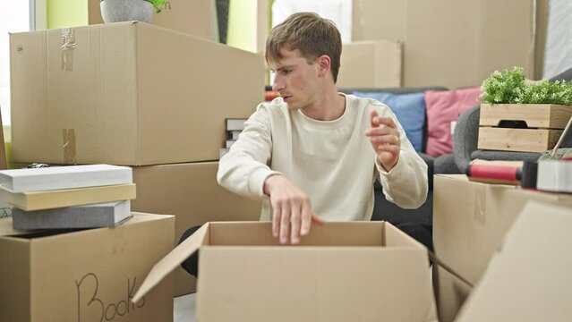 Young caucasian man packing cardboard box at new home