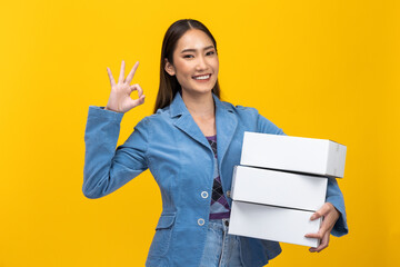 Happy Asian  entrepreneur woman holding package parcel box isolated on yellow background., Delivery courier and shipping service concept.