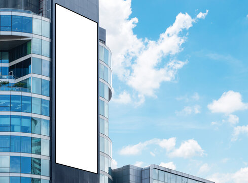 Mock Up White Large LED Display Vertical Billboard On Tower Building With Blue Sky Background. Clipping Path For Mockup